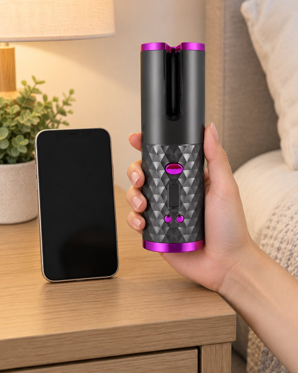 The curler held upright in one hand next to a phone