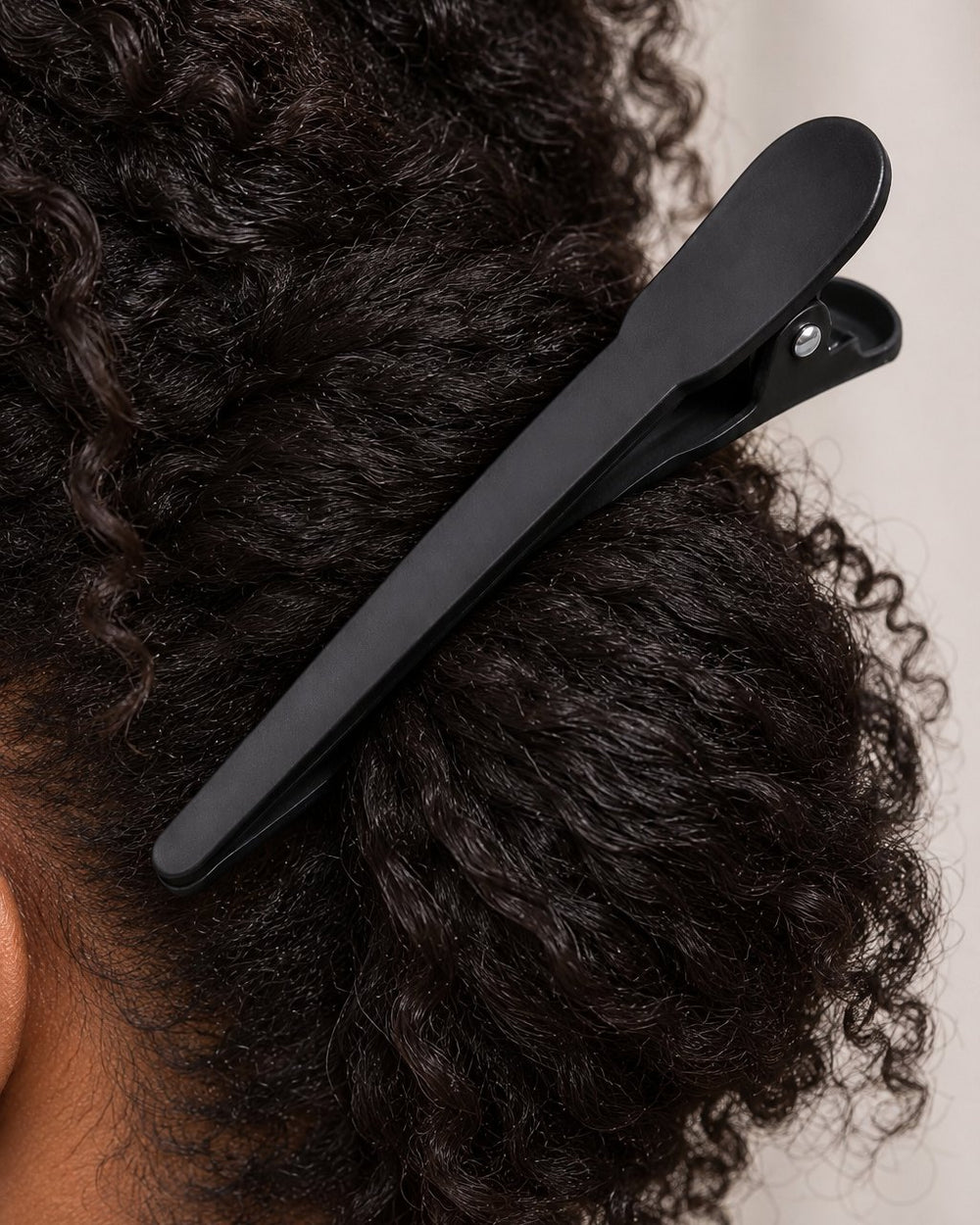 Close-up of a clip's long matte jaws gripping a thick section of hair