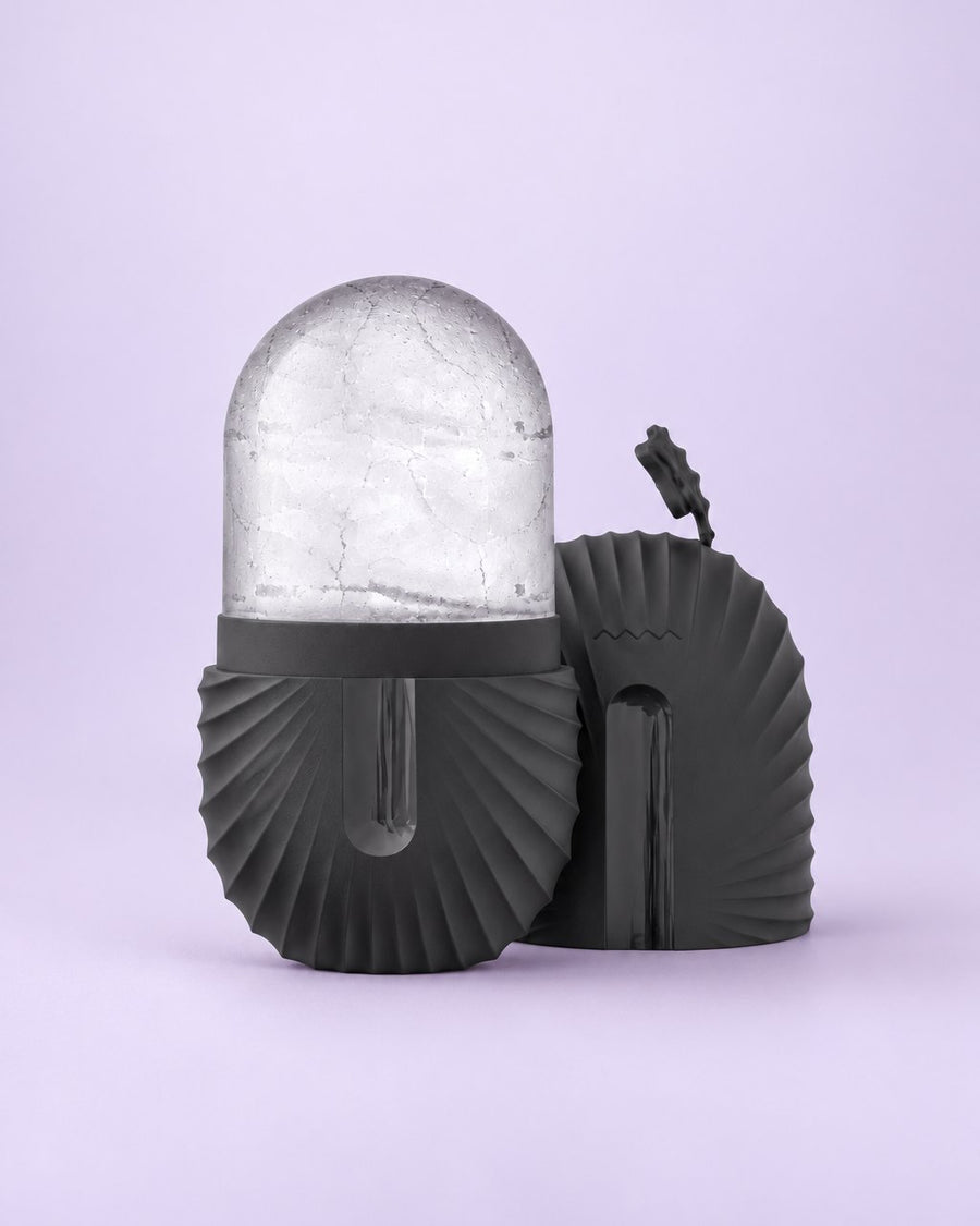 Black ribbed silicone ice capsule holding a clear dome of ice, cap beside it