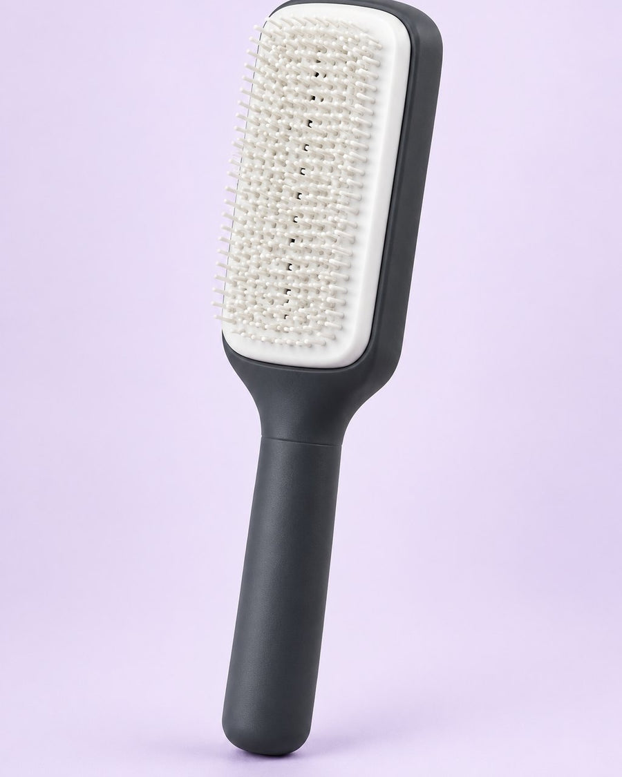 Charcoal self-cleaning paddle brush with a white cushioned pad