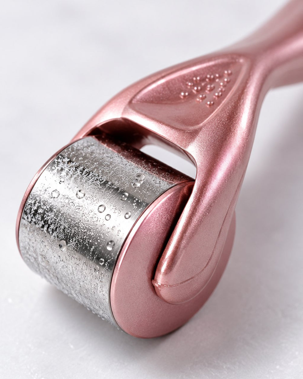 Close-up of the polished stainless steel roller head with a light frost