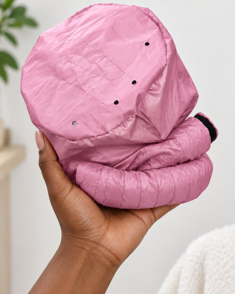 The pink bonnet with its hose coiled round it, held in one hand