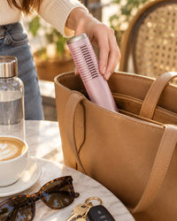 The capped comb going into an open tote bag next to sunglasses and keys