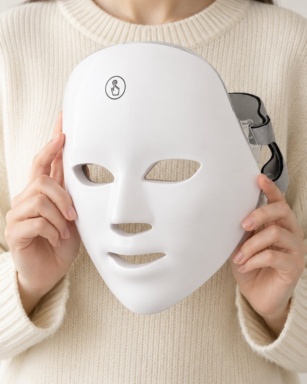 LED face mask held up in two hands, showing it covers a whole adult face