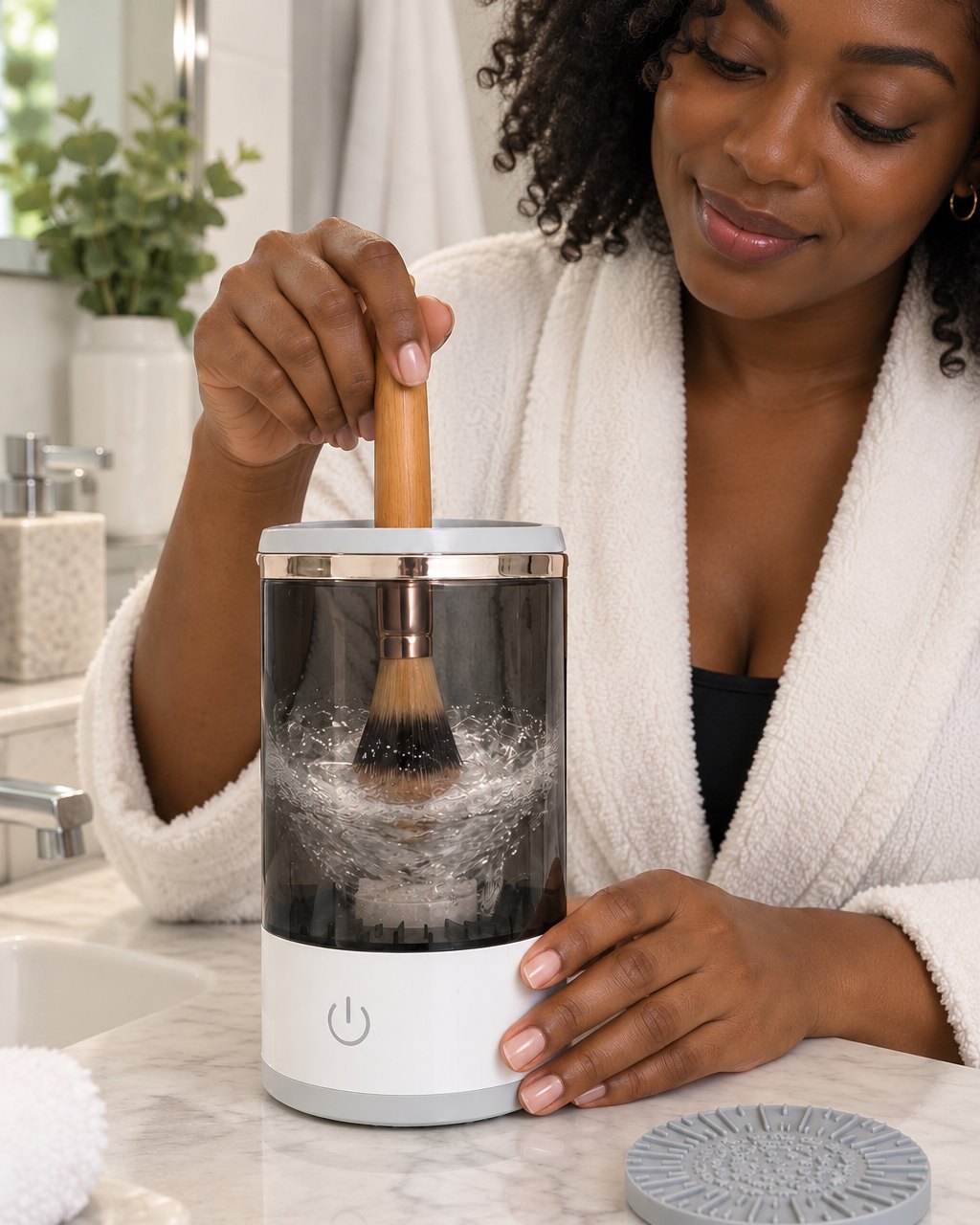 Hand holding a foundation brush in the swirling water of the brush cleaner jar