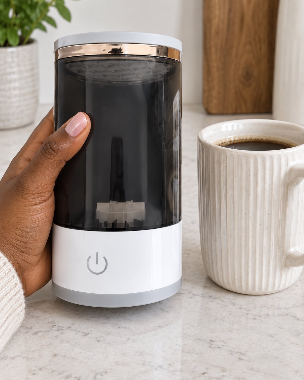 The brush cleaner held in one hand, about the height of a tall mug
