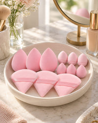 Pink sponges and puffs in a dish on a vanity beside a mirror