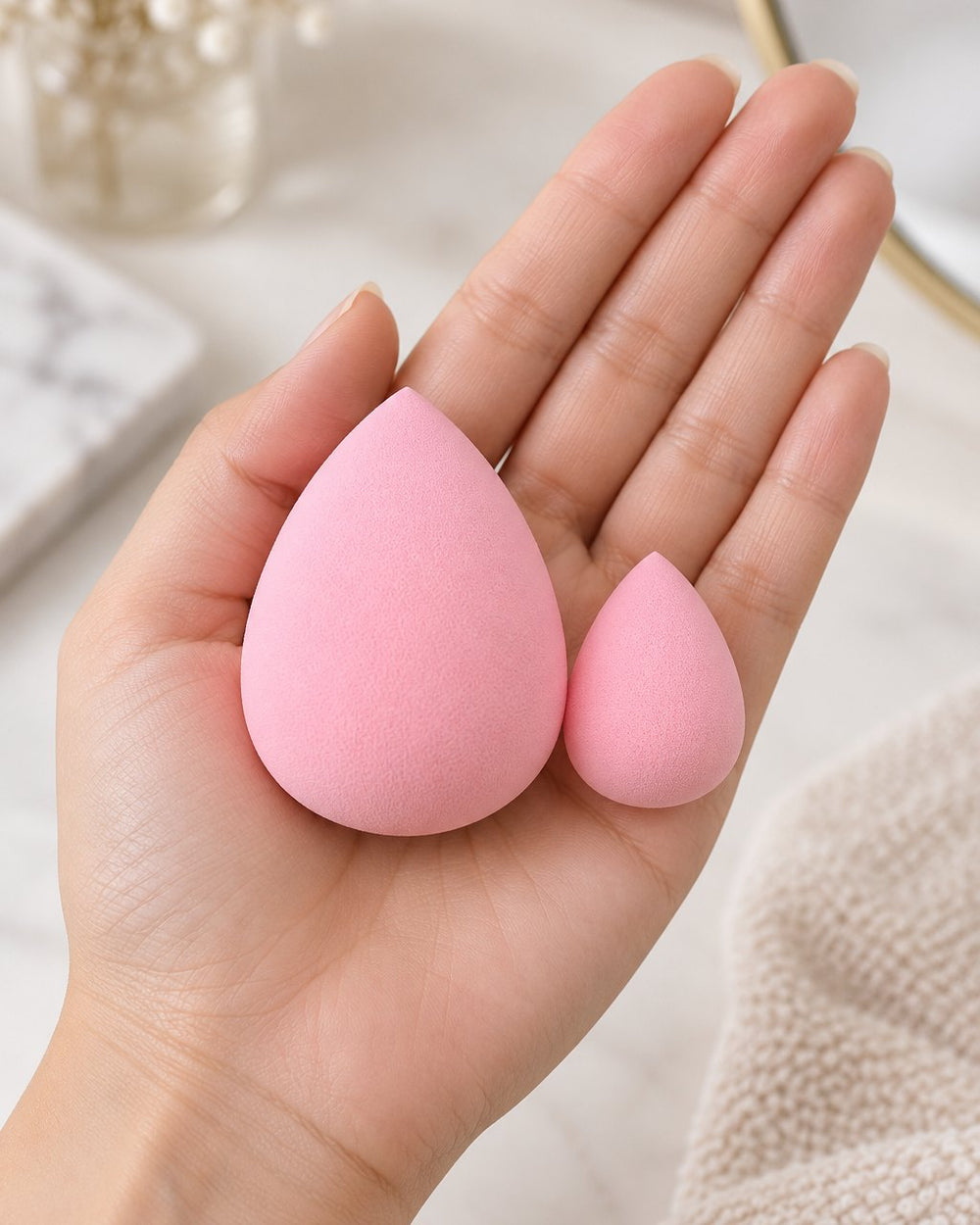 A teardrop sponge and a mini sponge resting in an open palm