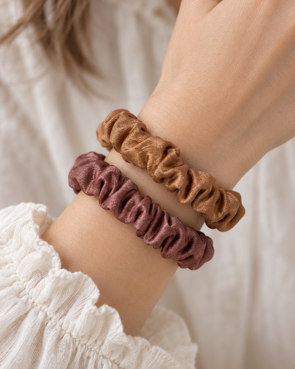 Two satin scrunchies worn on a wrist like bracelets