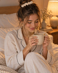 Woman in pyjamas with a loose bun held by a cream scrunchie