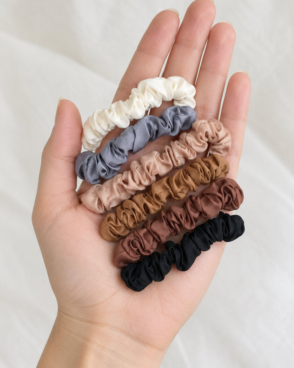 The six scrunchies held loosely in one hand