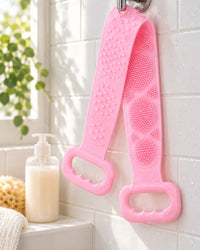 Pink scrubber strap hanging by one handle from a shower hook