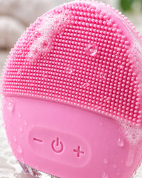 Close-up of the brush's soft pink silicone nubs with water droplets and a little foam