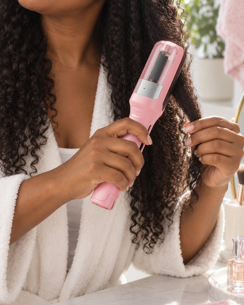 A woman glides the trimmer down a section of long, wavy brown hair