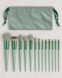 All thirteen sage green brushes laid out in a row beside the pouch