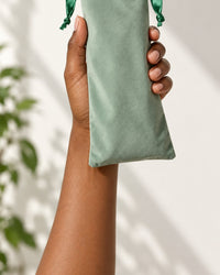 The closed drawstring pouch held in one hand